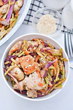 a white bowl filled with stir fry vegetables and meat next to a plate of rice