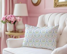 a white couch sitting next to a pink wall with a mirror on top of it