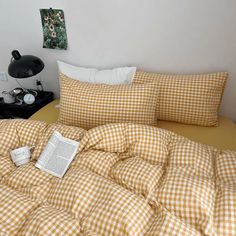 a yellow and white checkered comforter on top of a bed next to an alarm clock