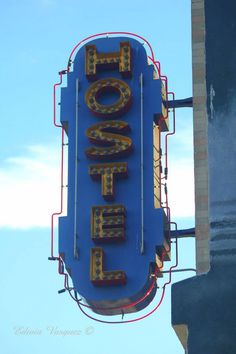 a sign that is hanging from the side of a building in front of a blue sky