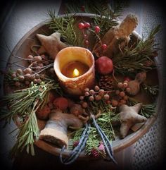 a candle is lit in the center of a bowl filled with branches and other decorations