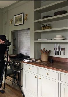 a man standing in front of a stove with a camera on a tripod next to it