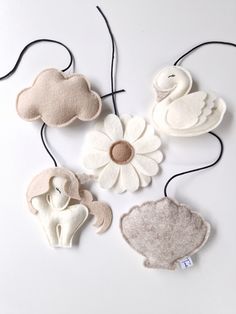 three felt flowers and two stuffed animals on a white surface with black string attached to them