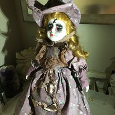 the doll is wearing a purple dress and hat