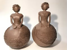 two clay sculptures sitting on top of each other in front of a white background,