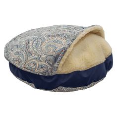 a dog bed with a blue and white paisley pattern on the front, it has a hood