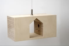 a wooden birdhouse hanging from the side of a wall with a light on it