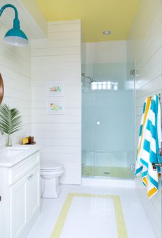 a white bathroom with yellow and blue accents