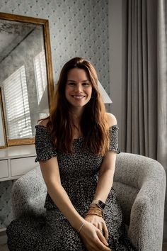 a woman sitting in a chair smiling at the camera