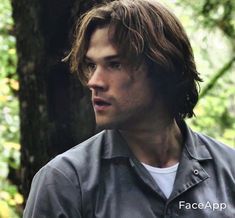 a young man standing in the woods looking at something