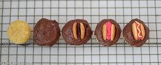 four chocolate donuts with different toppings on a cooling rack