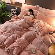 a woman laying in bed under a pink comforter