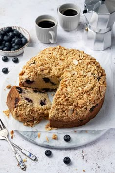 a blueberry crumb cake on a plate with two slices cut out and ready to be eaten