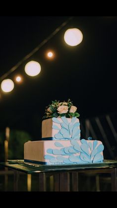 a blue and white cake sitting on top of a wooden table under some light bulbs