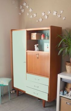 a wooden cabinet with drawers and shelves in a living room next to a small table