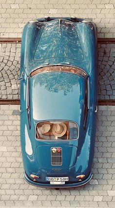 an overhead view of a blue car with two people sitting in the front seat and looking down