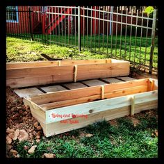 two wooden boxes sitting in the grass near a fence