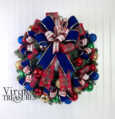 a christmas wreath with red, white and blue bows hanging on the wall next to a door