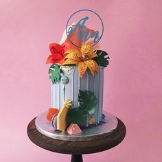 a multi - tiered cake is decorated with flowers and tropical leaves on a wooden stand