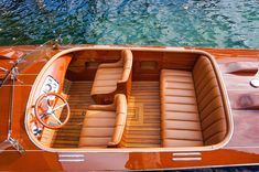 the inside of a small boat with two seats and steering wheel on the water's edge