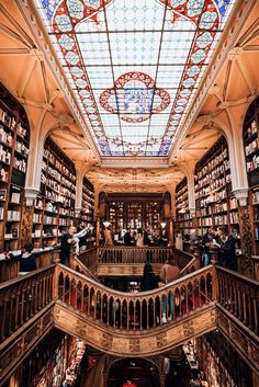 the inside of a library with many bookshelves and people standing on stairs in front of them