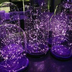 purple lights in glass vases sitting on top of a table