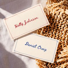 two business cards sitting next to each other on top of a pile of dried grass