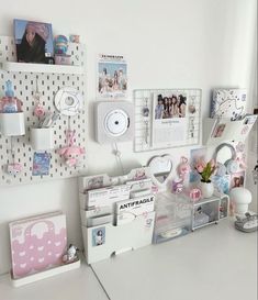 a white desk topped with lots of pictures and magnets on it's wall