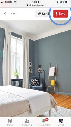 a bed room with a neatly made bed next to a window and a blue chair