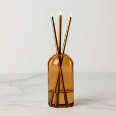 three candles in a glass vase on a marble surface