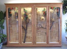 a wooden cabinet with glass doors and flowers on it