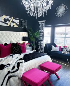 a bedroom decorated in black, white and pink with a chandelier above the bed