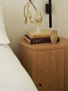 a nightstand with two books and a vase on it