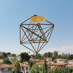 a kite flying in the air with houses in the background and trees on the other side