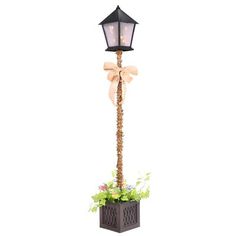 a lamp post with a bow on it and flowers in the planter next to it