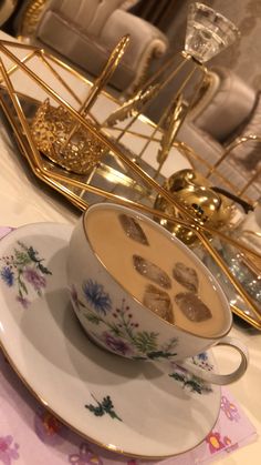 there is a cup and saucer on the table with gold trimmings around it