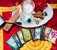 a table topped with cards and candles on top of a red cloth next to a candle