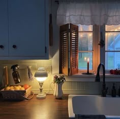 a kitchen sink sitting under a window next to a counter top with lights on it