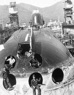 two men are standing in front of a large ship that is being built on land