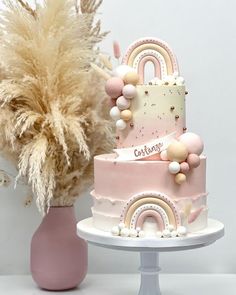 a three tiered cake sitting on top of a table next to a vase filled with flowers