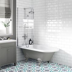 a bath tub sitting next to a white sink in a bathroom with blue and white tiles on the floor