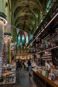 people are browsing at the book store in an old cathedral like building with high vaulted ceilings