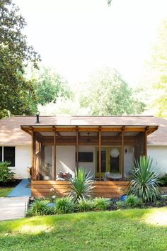 a small white house sitting in the middle of a lush green yard with lots of trees