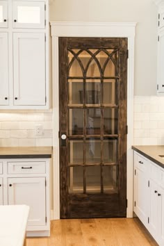 an open glass door in a kitchen with white cabinets