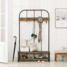 an iron and wood coat rack with shoes, purses and hats hanging on it