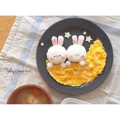 two little bunnies sitting on top of a black plate