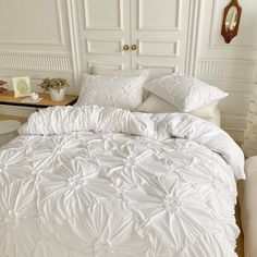 a bed with white comforters and pillows in a room