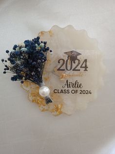 an award badge with flowers and pearls on the back of it, sitting on a white table cloth