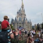 a group of people standing in front of a castle with a child on his back