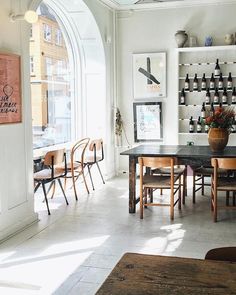 a dining room table and chairs with bottles on the wall